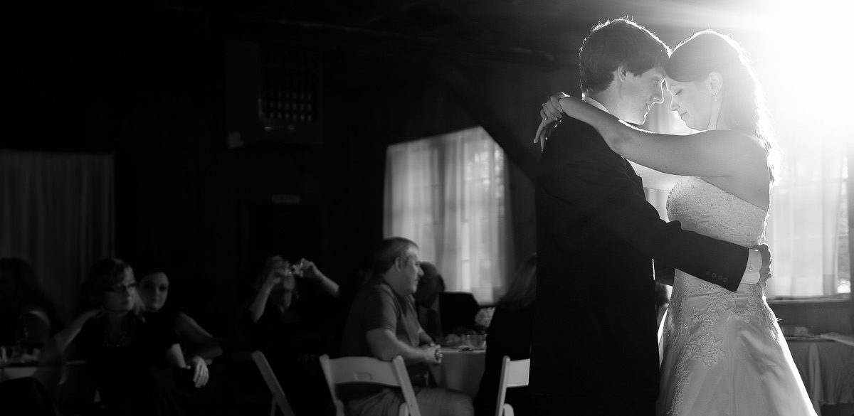 Black and White image of a bride and groom during their first dance with dynamic lighting
